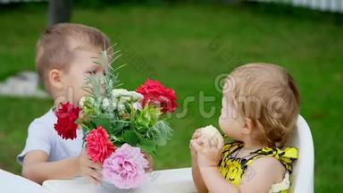 夏天，在花园里。这个四岁的男孩把一束花送给他一岁的妹妹，弟弟